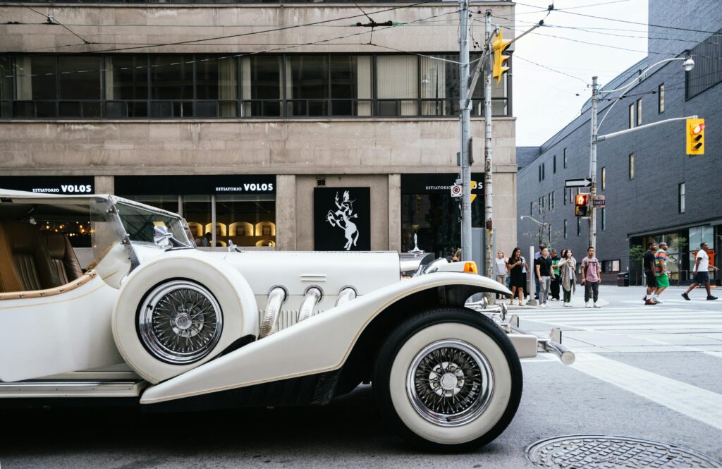 Vintage white limousine parked on an urban street corner with pedestrians in the background.